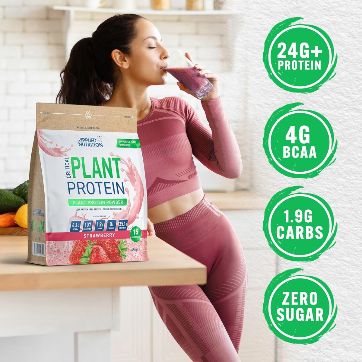 Woman in pink athletic wear drinking a protein shake next to a bag of Critical Nutrition plant protein powder.
